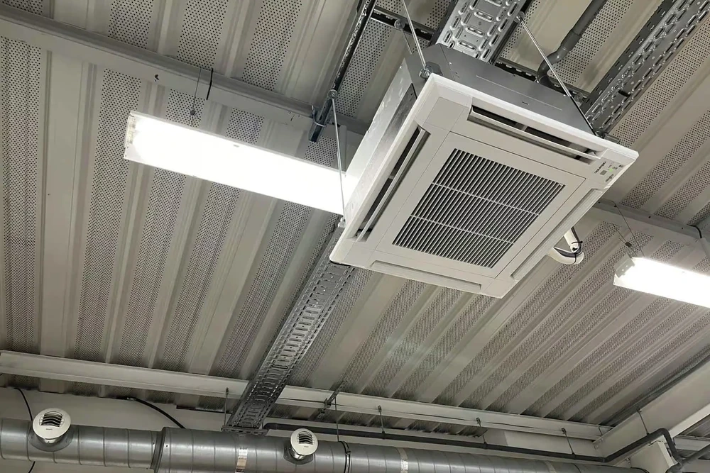 Plafond suspendu en construction avec ossature métallique apparente et plaques de plâtre perforées