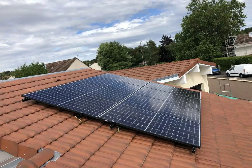 Chantier extérieur d'installation de panneaux solaires photovoltaïques sur toiture résidentielle en tuiles terre cuite